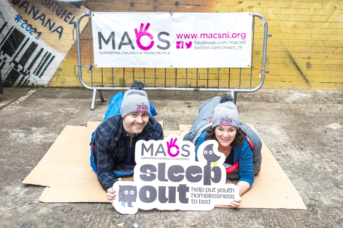 Kate and Paddy in sleeping bags holding sleepout sign